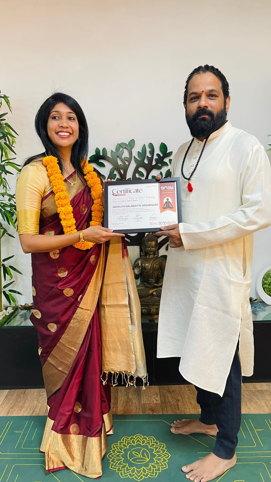 Jagruthi receiving her framed yoga teacher training certificate from her teacher at the Bodhi School of Yoga